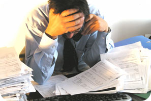Image of man overwhelmed by paperwork.